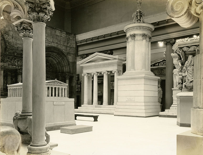 A historical museum interior featuring classical columns, architectural models, and sculptures, showcasing ancient Greek and Roman art.