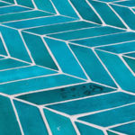 close-up view of blue terra cotta tile laid in a herring bone pattern.