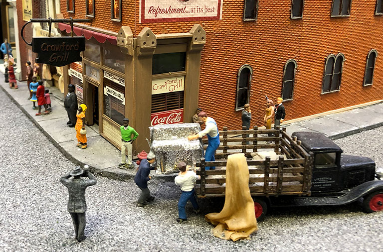 Scene depicting men unloading a piano and a photographer taking a photo.