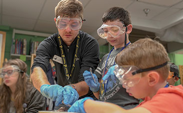 Two young boys dissect a sheep brain with the help of instructor.