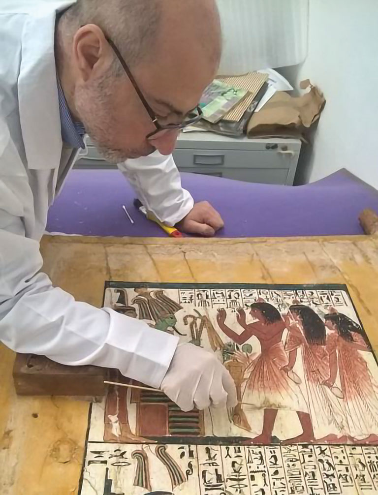 A man working on an ancient doorway of a tomb.