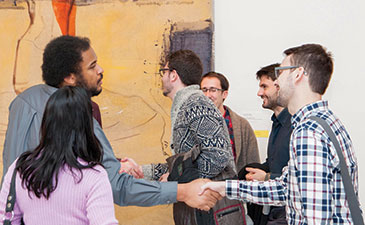 A group of museum-goers greeting each other in front of a large painting in the gallery.