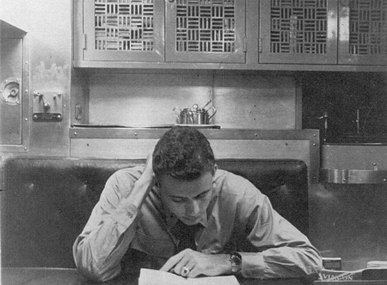 a vintage photo of a man reading in his room aboard a submarine.