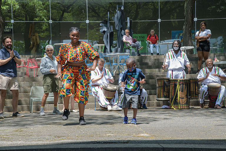 people dancing with musicians behind them in an outdoor setting.