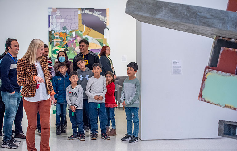 An art museum educator leading a tour of immigrant families through the museum.