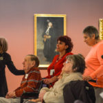 A docent leading a group of Alzheimer patients on a tour of an art gallery