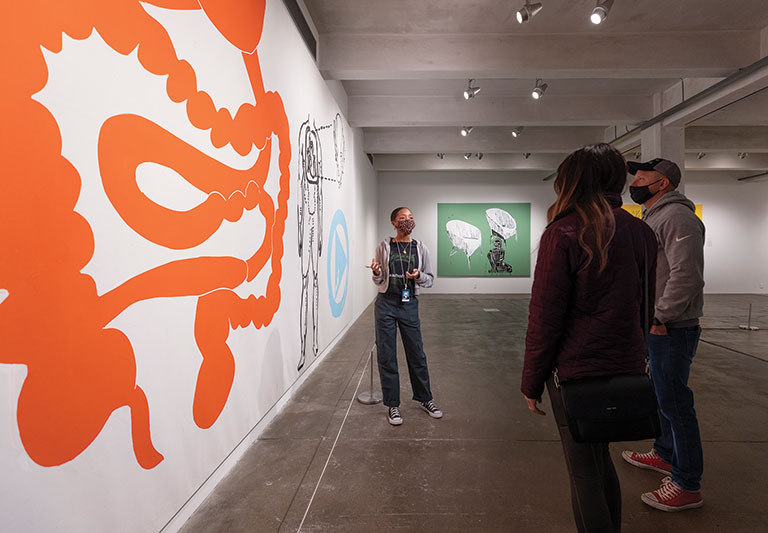 A gallery assistant at the Warhol museum speaking with two museum visitors