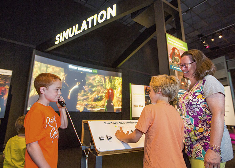 A group of museum goers interacting with a Pixar exhibit.
