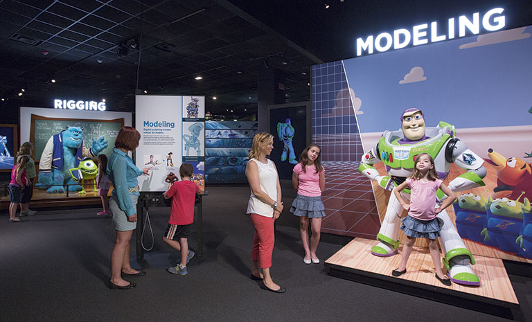 A group of museum goers interacting with a Pixar exhibit.