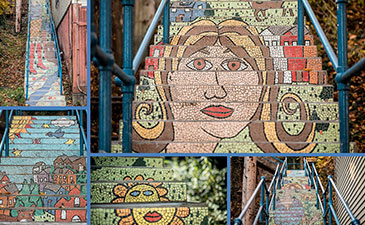 Colorful mosaic staircase featuring abstract faces, landscapes, and patterns, blending art with a public space setting.