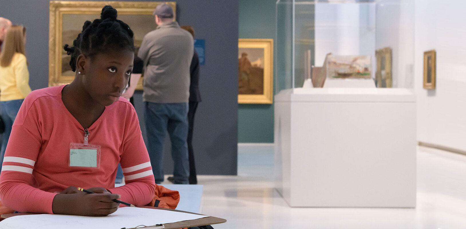 A Black teenager drawing in the art museum