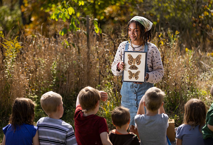 An educator presenting with a case of butterflies to a group of young children
